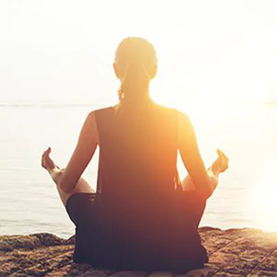 Frau meditiert im Sonnenaufgang
